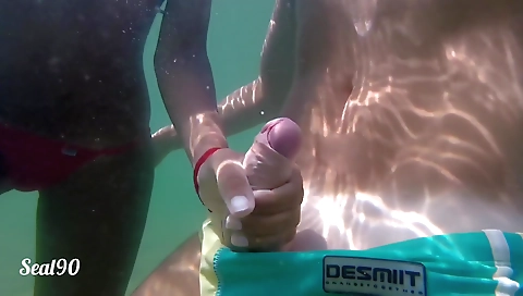 Latina teen in a public beach gets a handjob under the waves